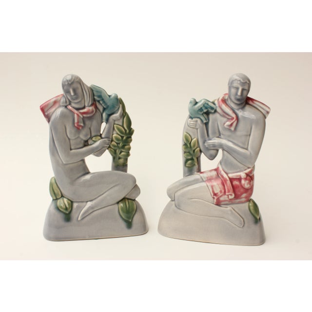 Pair of very fine Art Deco ceramic sculptures depicting highly-stylized male and female figures, each holding doves. The...