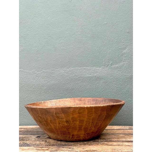 This vintage bowl is a monumental, hand-carved vessel with a broad, softly oval form that flares from a narrow, flat foot...