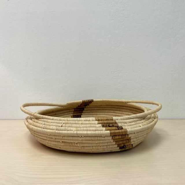 This dramatic, extra wide and shallow basket is made from natural undyed raffia and banana fibers by talented women in...