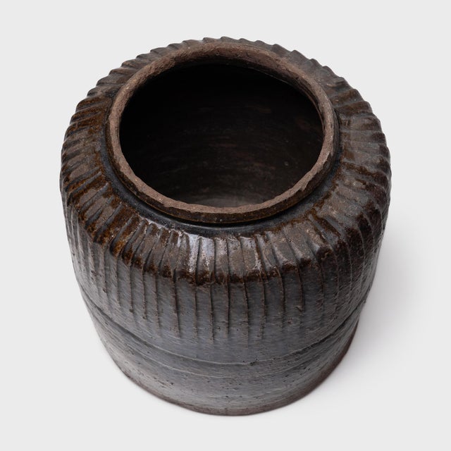 Cloaked inside and out with a dark brown glaze, this ceramic vessel from the early 19th century was originally used in a...