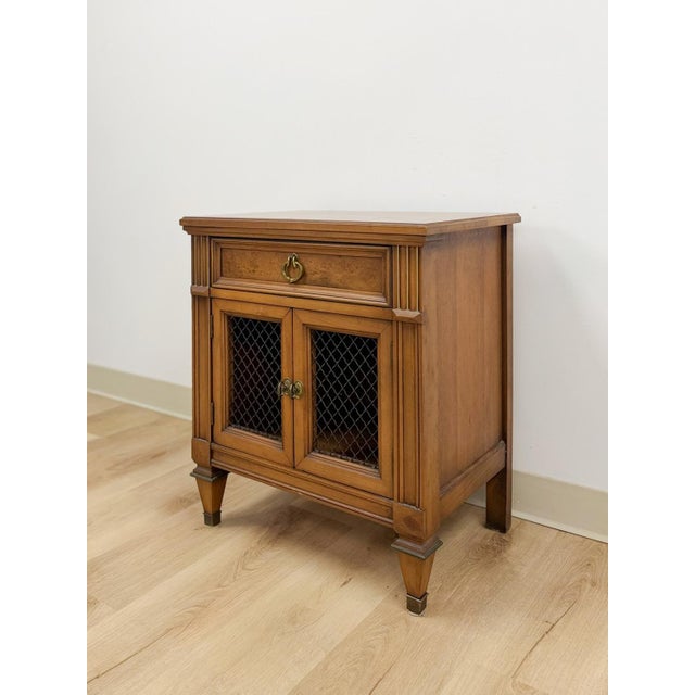This distinctive vintage MCM transitional nightstand is a well-made and characterful bedside find. The iron grate cabinet...