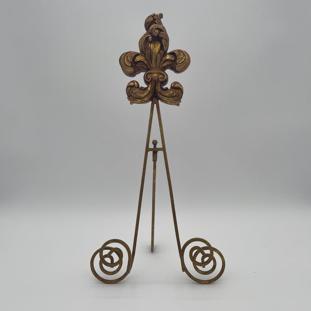 Gold gilt tabletop plate stand or picture easel with scrolled ironwork and a Fleur de lis crest