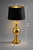 An elegant Hollywood Regency brass urn table lamp featuring its striking original black drum shade with luminous gold...