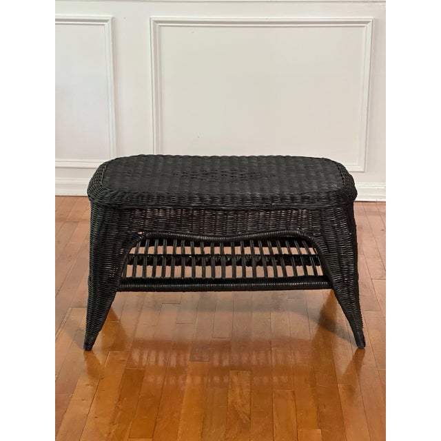 Shapely French natural wicker coffee table with a lower shelf in a black painted finish, circa late 1960-70s. It features...