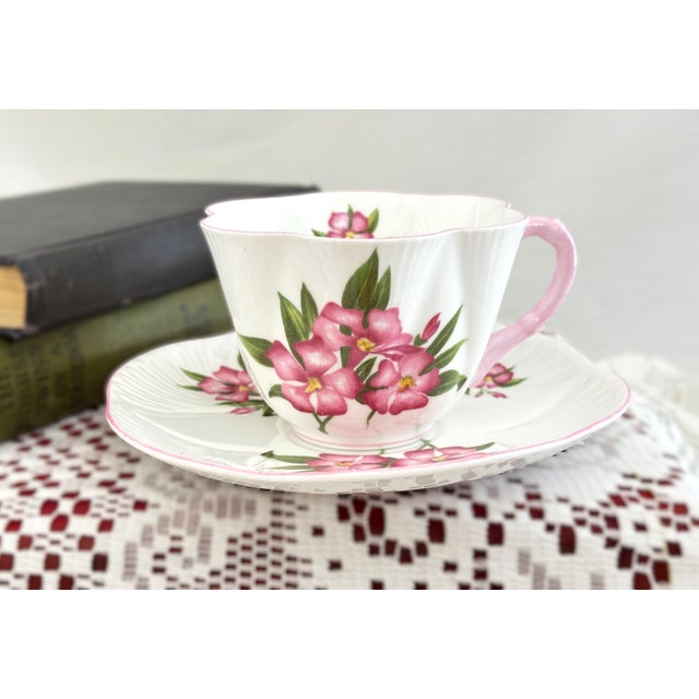This Dainty Shape Shelley tea cup is decorated in the pink Oleander pattern (No. 13883). Made of fine English bone china,...