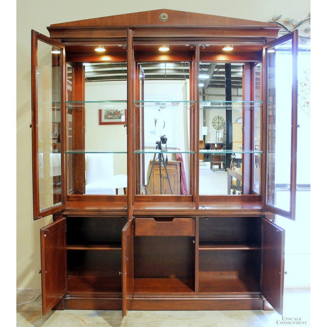 This piece features a traditional silhouette with a prominent medallion crown and a warm hardwood finish. The upper hutch...