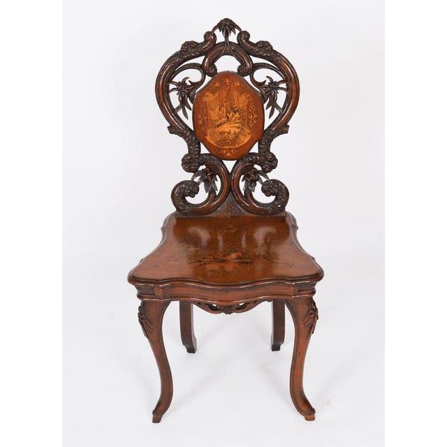 This is a superb antique 19th Century Swiss carved walnut and marquetry inlaid musical chair. It has a striking bold leaf...