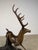 A dramatic bronze stag sculpture captured mid-motion, this piece depicts a powerful deer bounding over a naturalistic tree...