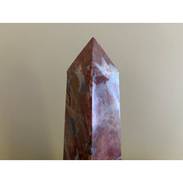 A beautifully proportioned marble obelisk in richly veined shades of red, cream, and brown. The sculptural silhouette and...