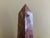 A beautifully proportioned marble obelisk in richly veined shades of red, cream, and brown. The sculptural silhouette and...