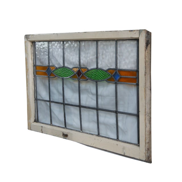 A charming early 20th Century Arts & Crafts leaded stained glass window panel. Features a geometric center of green ovoids...