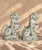 A striking pair of vintage Chinese foo dog figurines featuring expressive guardian lion forms, intricate sculptural...