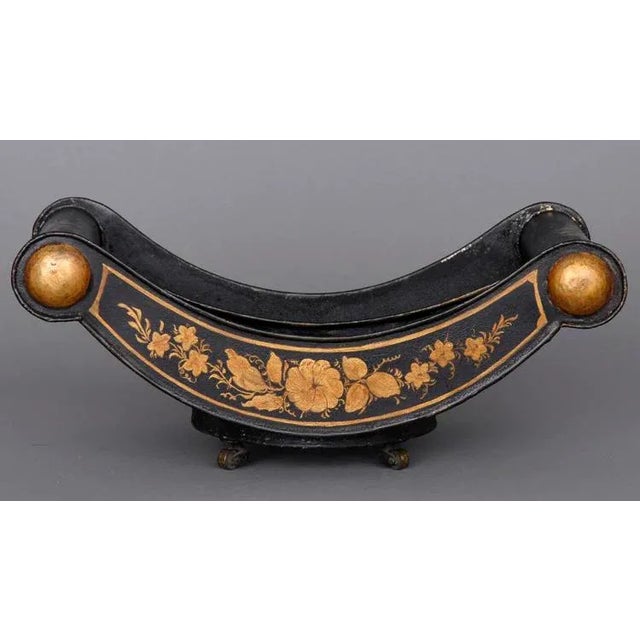 Regency tole cheese coaster painted black with gilded floral decoration on both sides and small Georgian casters on the...