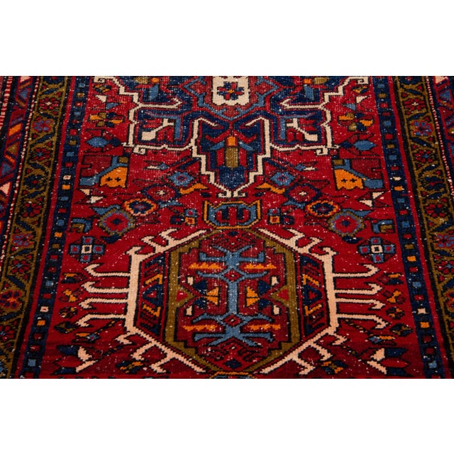 Beautiful vintage Persian Heriz hand-knotted wool runner with a red field. This Persian rug has a brown frame and...