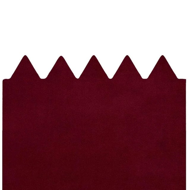 The Moody Red Rug features triangular shapes along the border in deep burgundy, evoking passion, strength, and bold...