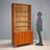 Larch veneered storage unit with brass accents, featuring a display case and hinged doors. In good overall condition, it...