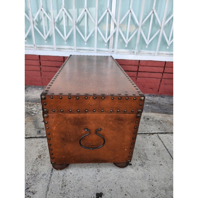Leather-covered storage trunk with a brown finish. This chest has decorative brass nailhead trim along the edges and a...