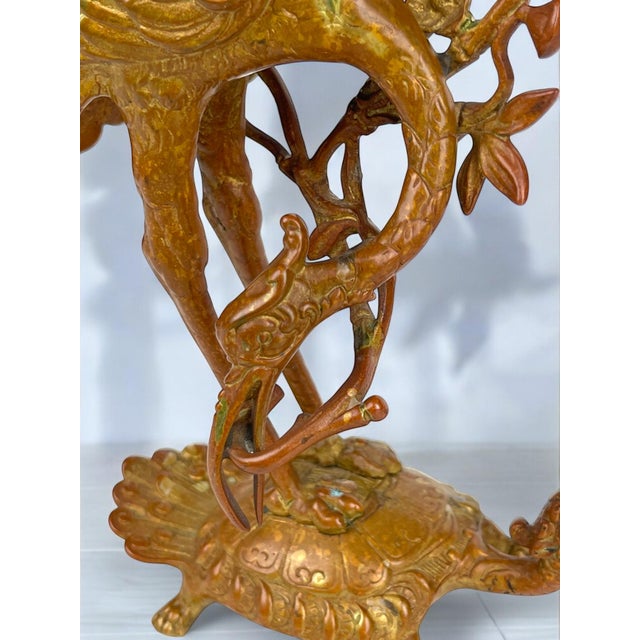 A pair of gilt bronze candlesticks from the 19th century. They are in the form of a crane or heron standing on the back of...