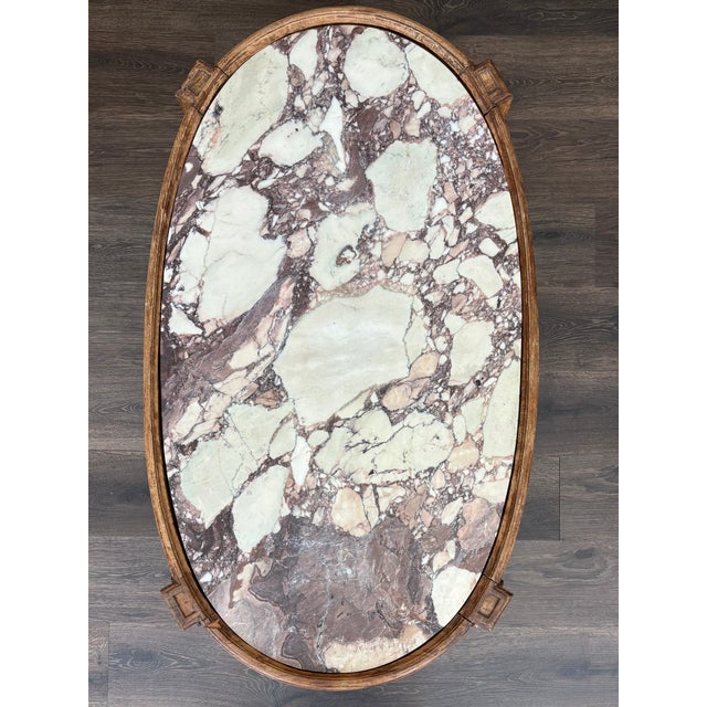 Neoclassical oval coffee table with a beautiful hand carved European oak base and Italian marble top.. The.marble features...