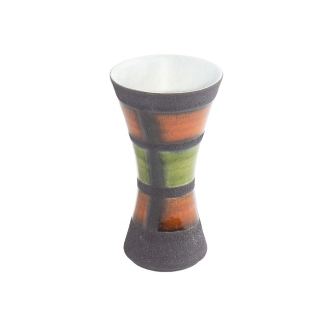 A West German ceramic vase produced by Dümler and Breiden. This mid-century vase tapers at the center and has a black grid...