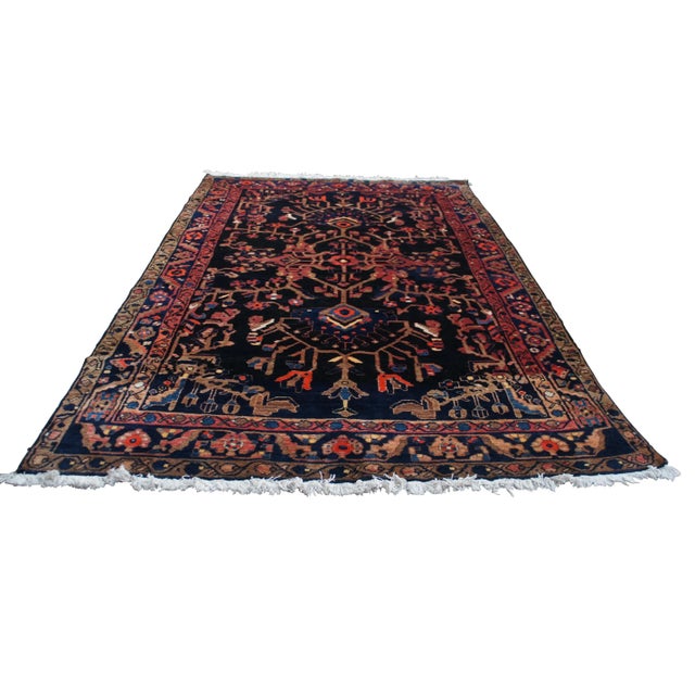 Vintage Oriental tribal rug or carpet. Made of wool featuring a floral vine motif with a dark field contrasted with reds...