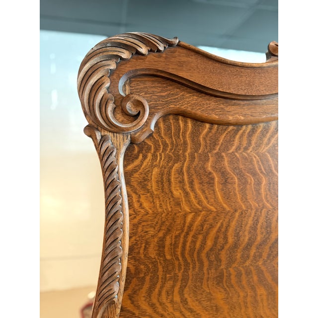 Antique tiger oak bed frame featuring a high-back headboard with a carved crest and a rolling pin footboard with...