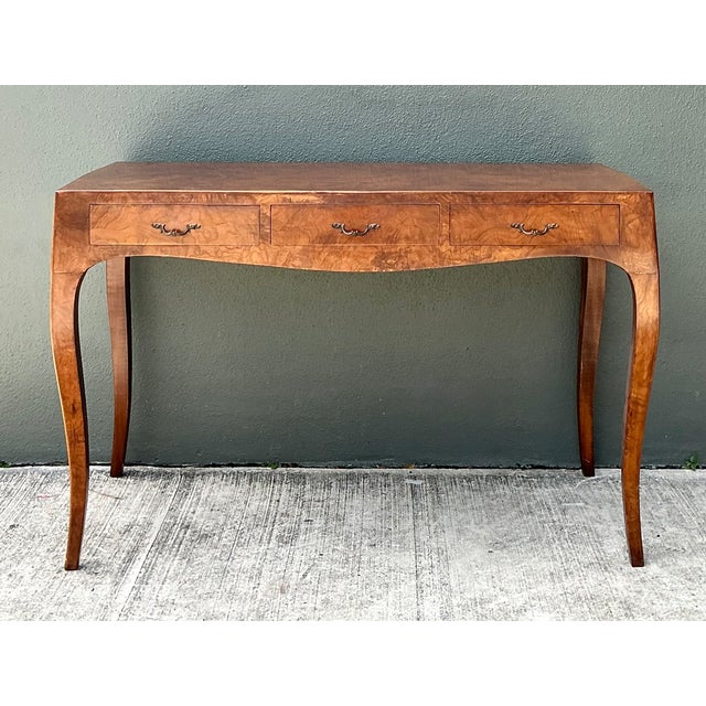 This vintage Italian writing desk showcases rich burl wood with swirling, honey-toned grain across its desktop, paired...