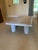 A large and heavy rectangular travertine stone coffee table with a beveled edge, four stout cylindrical legs and a chunky,...
