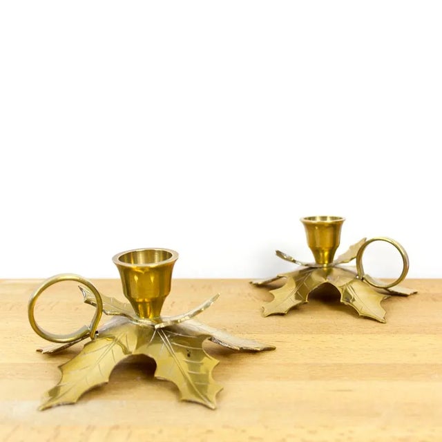 A pair of low candleholders made of brass in the shape of oak tree leaves.