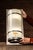 A striking ecclesiastical wall sconce built around a tall cylindrical opaline glass shade framed in steel bands and...