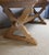 Large whitewashed oak table resting on an X-shaped base. The tabletop shows signs of wear, however, the overall condition...