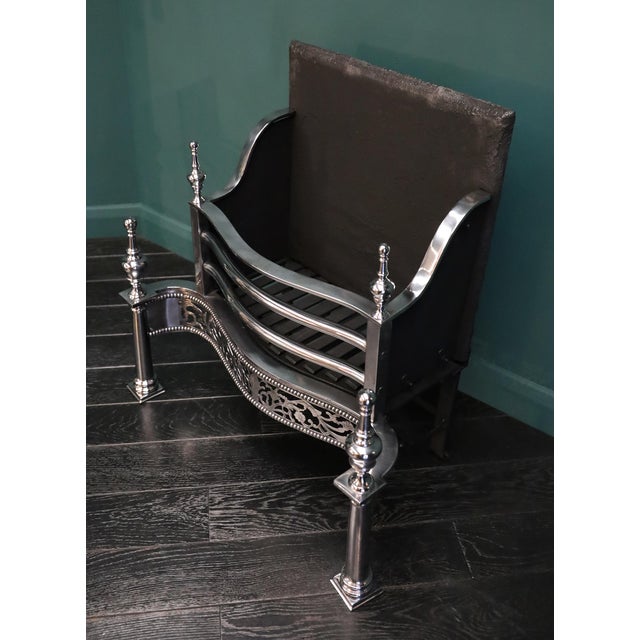 A free-standing polished steel fire grate in the Georgian form. The railed fire basket with three fire bars over an ornate...
