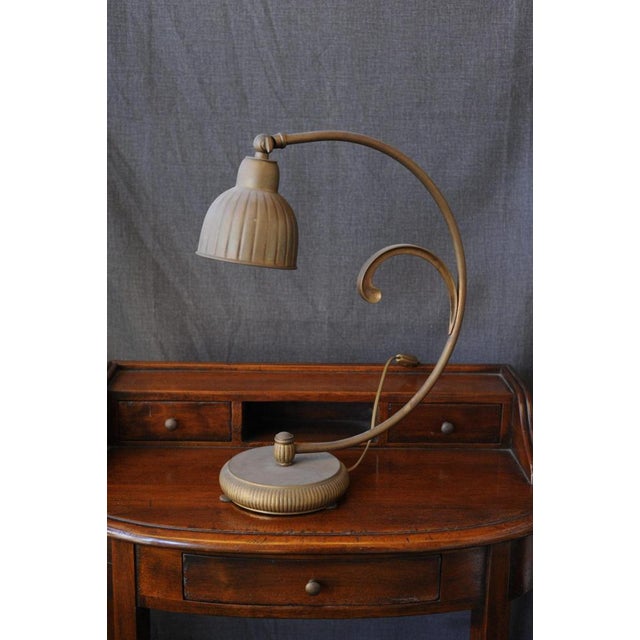 Bronze Lamp. A delicate lamp entirely made of bronze, its distinctive broad semicircular shape is evident. The downward-...