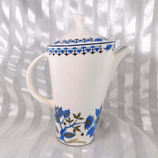 This is a white Nueva San Isidro coffee pot with a blue patterned rim and blue floral design. It is from Mexico and I do...