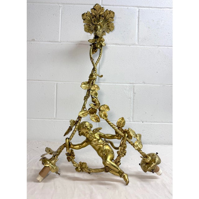 This large antique ornate gilt bronze hanging cherub chandelier is a stunning piece of architectural lighting. The...