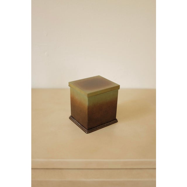 Patinated bronze the box has a decorative rope decoration around the fot. Very decorative and with the designers initials...