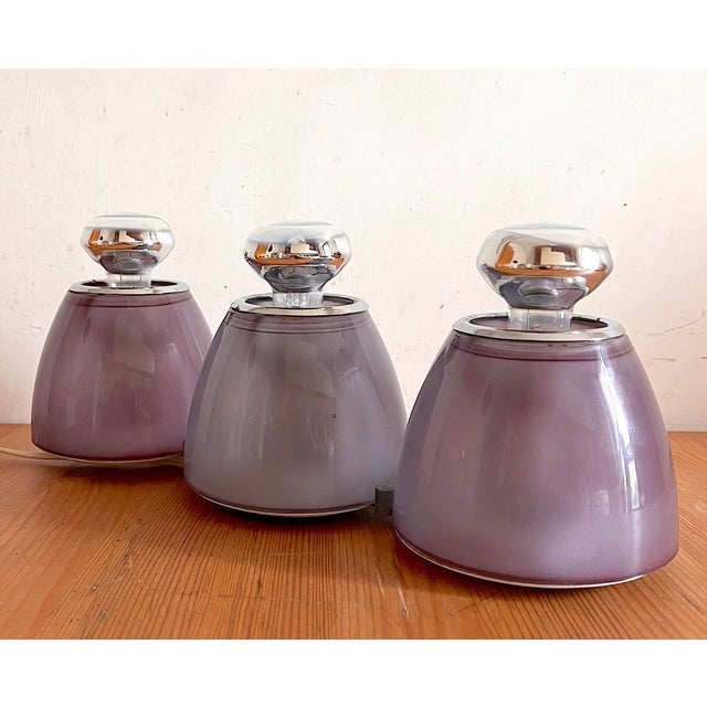 Wall lamp in plum-colored blown glass. Composed of three elements anchored in a straight line on a metal structure. It can...