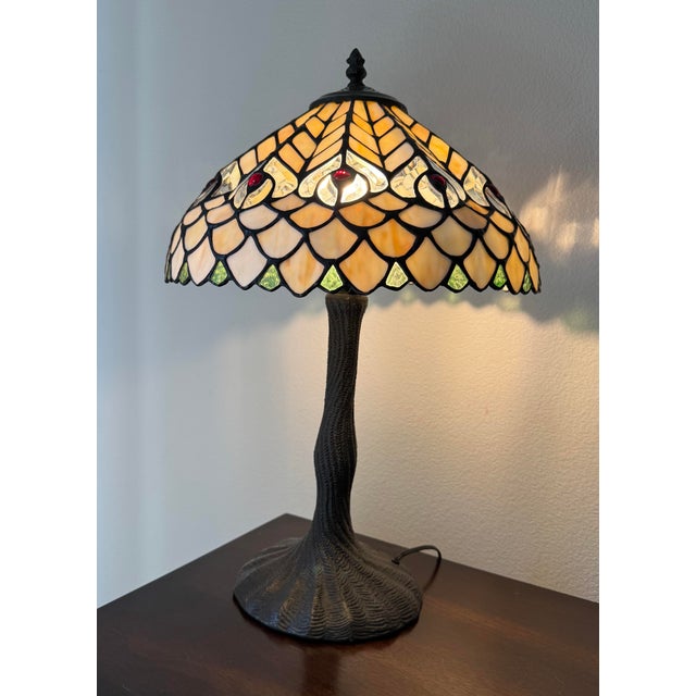 Tiffany Style Peacock Series stained glass table lamp featuring a shade with a fishscale pattern and a base resembling a...