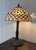Tiffany Style Peacock Series stained glass table lamp featuring a shade with a fishscale pattern and a base resembling a...