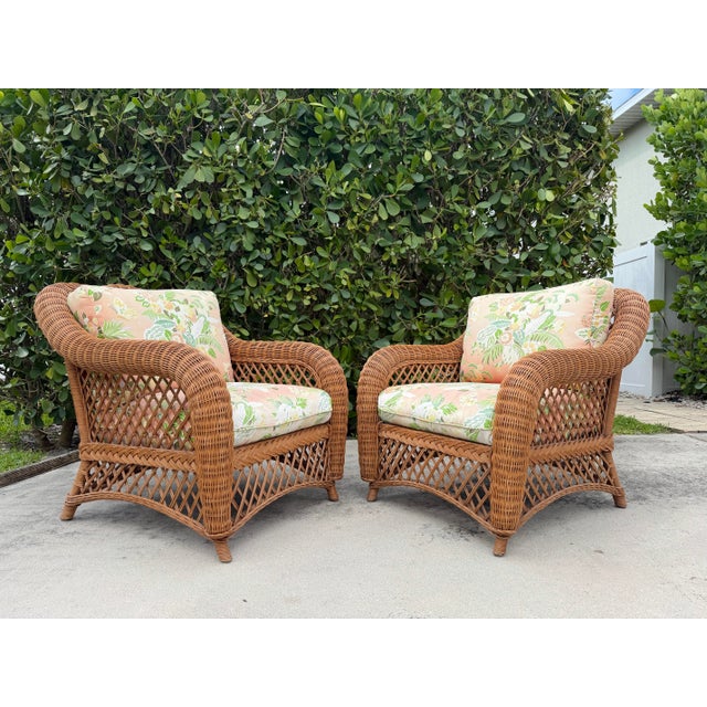A handsome pair of Palm Beach style wicker lounge chairs featuring substantial rolled arms, open lattice sides and backs,...