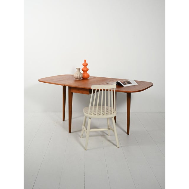 1950s table with two independent extension leaves, a slender frame, and a teak top with rounded edges. Functional...