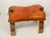 Gorgeous Moroccan antique handmade camel saddle footstool with bronze bell and metal embellishments on the wooden legs.
