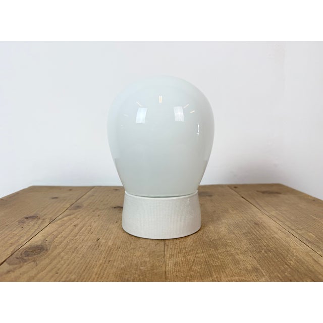 Vintage industrial ceiling or wall light made in former Czechoslivakia during the 1970s. It features a white porcelain...