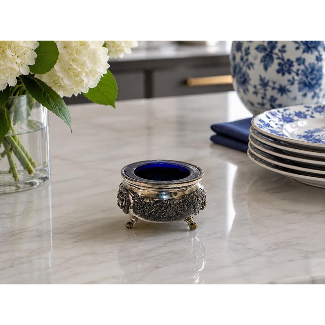 A charming vintage silverplate footed vessel with cobalt blue glass insert, featuring richly detailed floral repoussé...