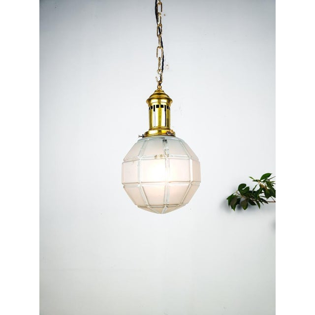 Early 1900’s brass and etched glass globe pendant from France. Suspended from a brass gallery is an etched glass globe...