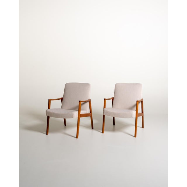 A pair of Scandinavian armchairs from the 1950s and 1960s with a solid teak frame and padded seat and backrest,...