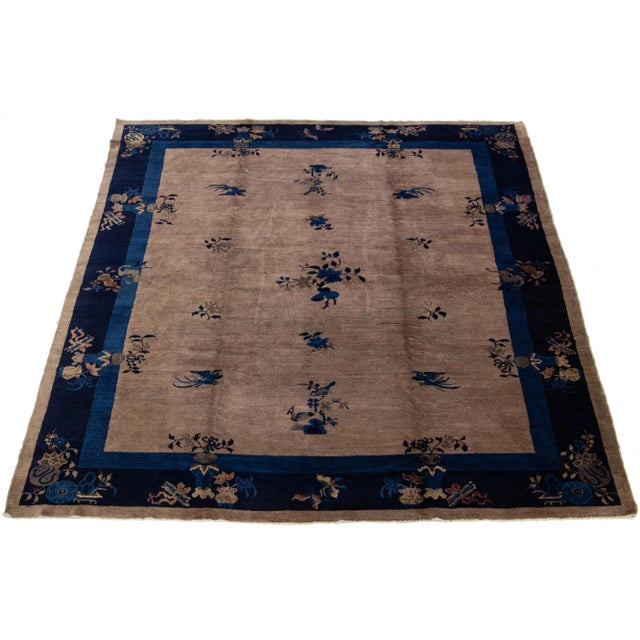 This hand-knotted wool Antique Chinese Art Deco rug features a floral design with black hues on a brown background and a...