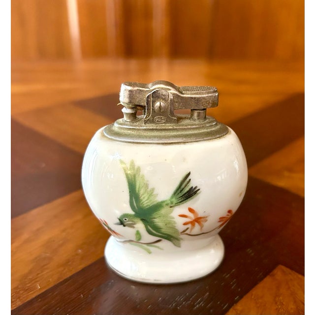 Offering a porcelain lighter hand painted with birds front and back