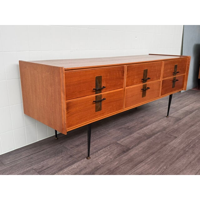 Large chest of drawers made in Italy in the 1950s. Teak veneer frame and metal legs with brass tips. It features clean...