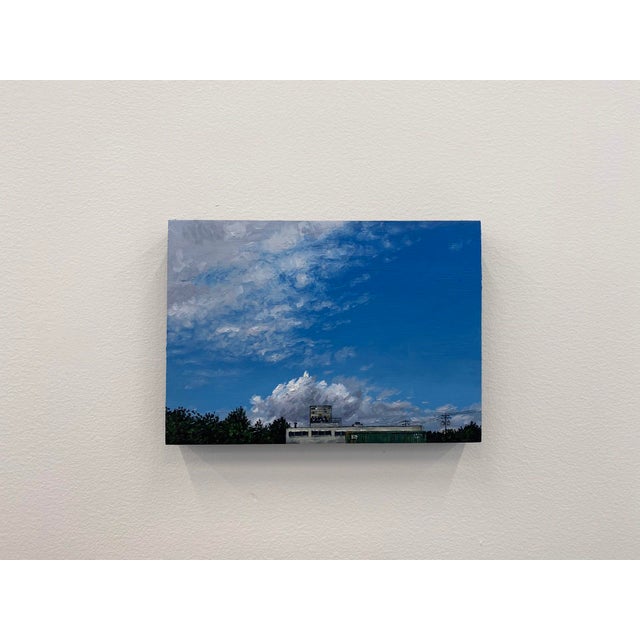 This oil painting captures a serene landscape featuring a building set against a vibrant sky, where fluffy clouds drift...